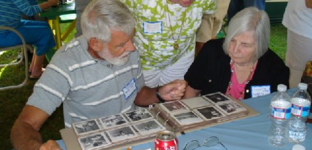 2 women and a man look at photographs