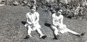 two young girls sit on lawn