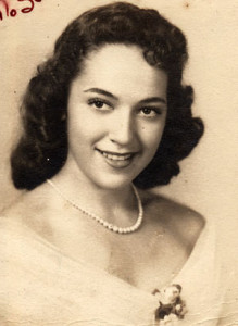 Young woman with dark hair, pearl necklace, and elegant dress