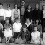 3 rows of children, boys and girls, with their teacher