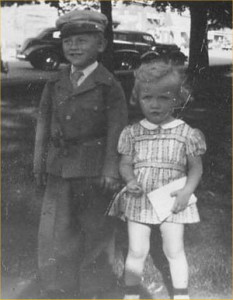 small boy, with cap, and girl in white-collared dress
