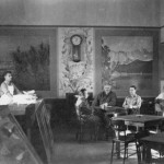 view of canteen, with 4 men seated and one man behind counter to left