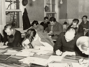 group of men at tables, studying and writing