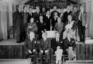 group of men on and in front of stage; one man holds small white dog