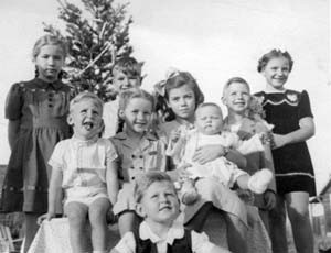 group of small children in front of spindly Christmas tree