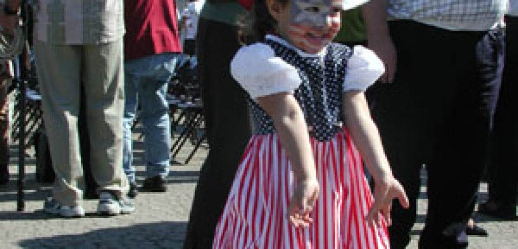 little girl with red, white, and blue dress and flags for Japan, Germany, and Italy in her hair