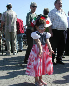 little girl with red, white, and blue dress and flags for Japan, Germany, and Italy in her hair