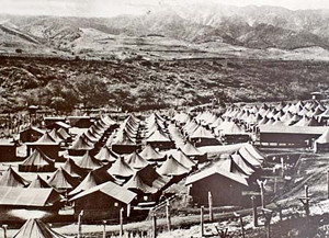 overview of a tent "city" behind barbed wire fences