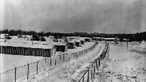 one story buildings in the snow with two barbed wire fences on perimeter