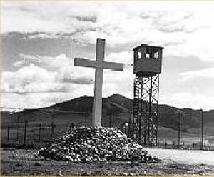 large cross, with guard tower and fence in background