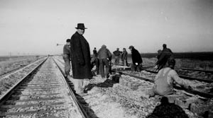 men working on railroad track; several men simply standing there, looking at them