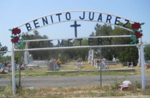 cemetery sign with graves behind wire fence